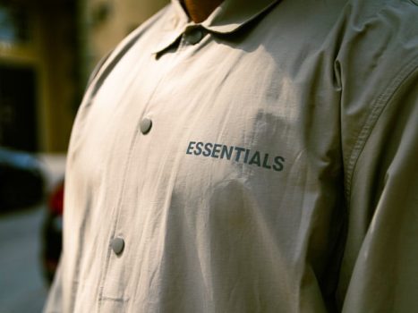 un homme porte une chemise grège avec un logo de la marque sur le cœur